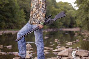 Umarex Synergis air rifle held by a hunter crossing a creek